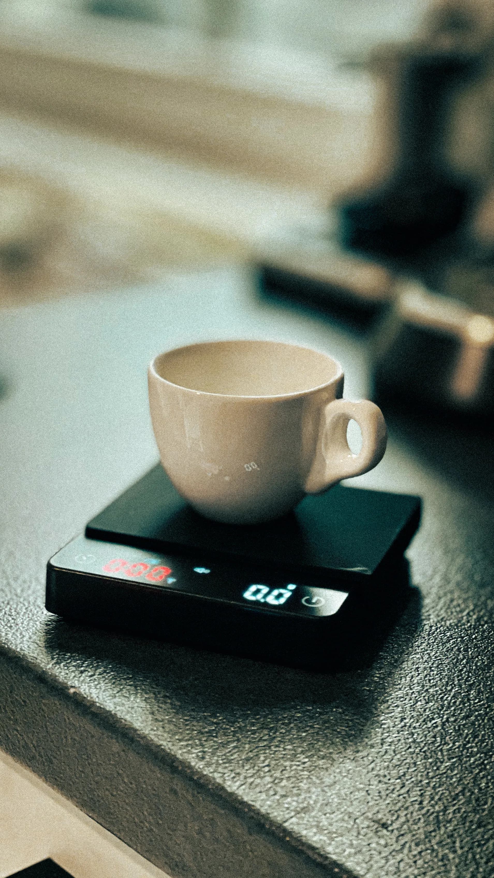 White coffee cup on a digital scale beside an espresso machine