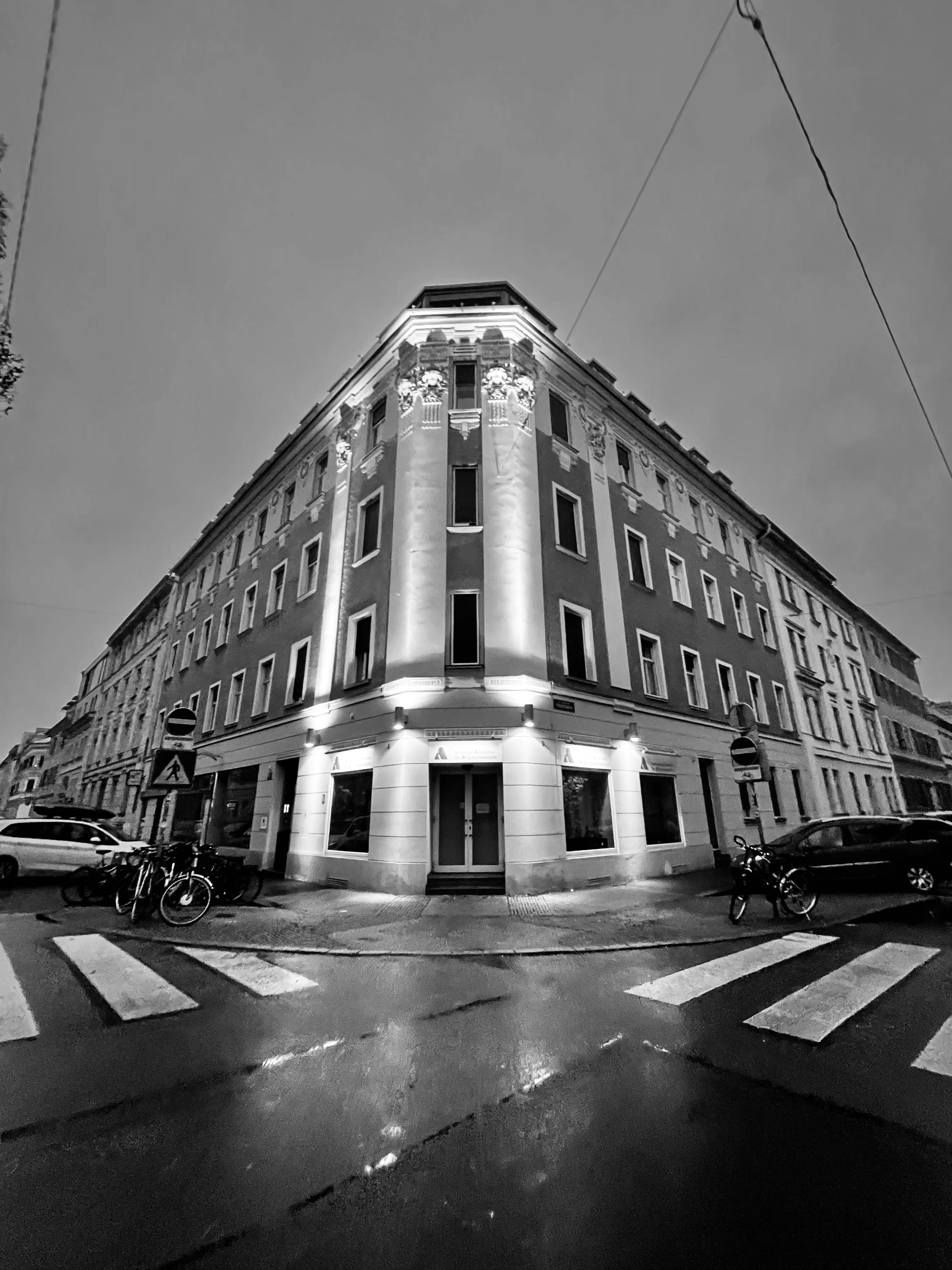 Black-and-white corner building overlooking a wet intersection