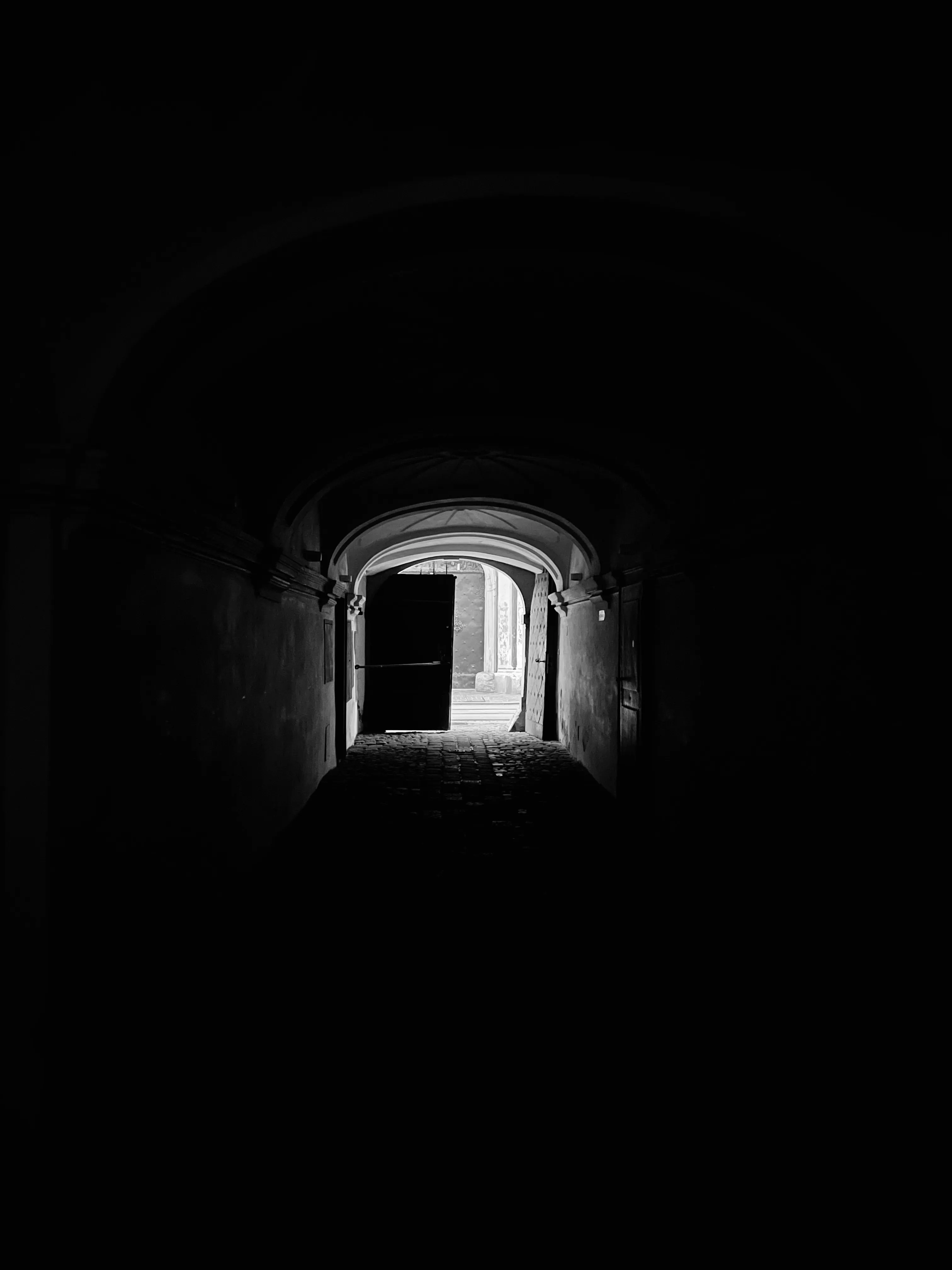 Dark vaulted passage opening onto a bright doorway