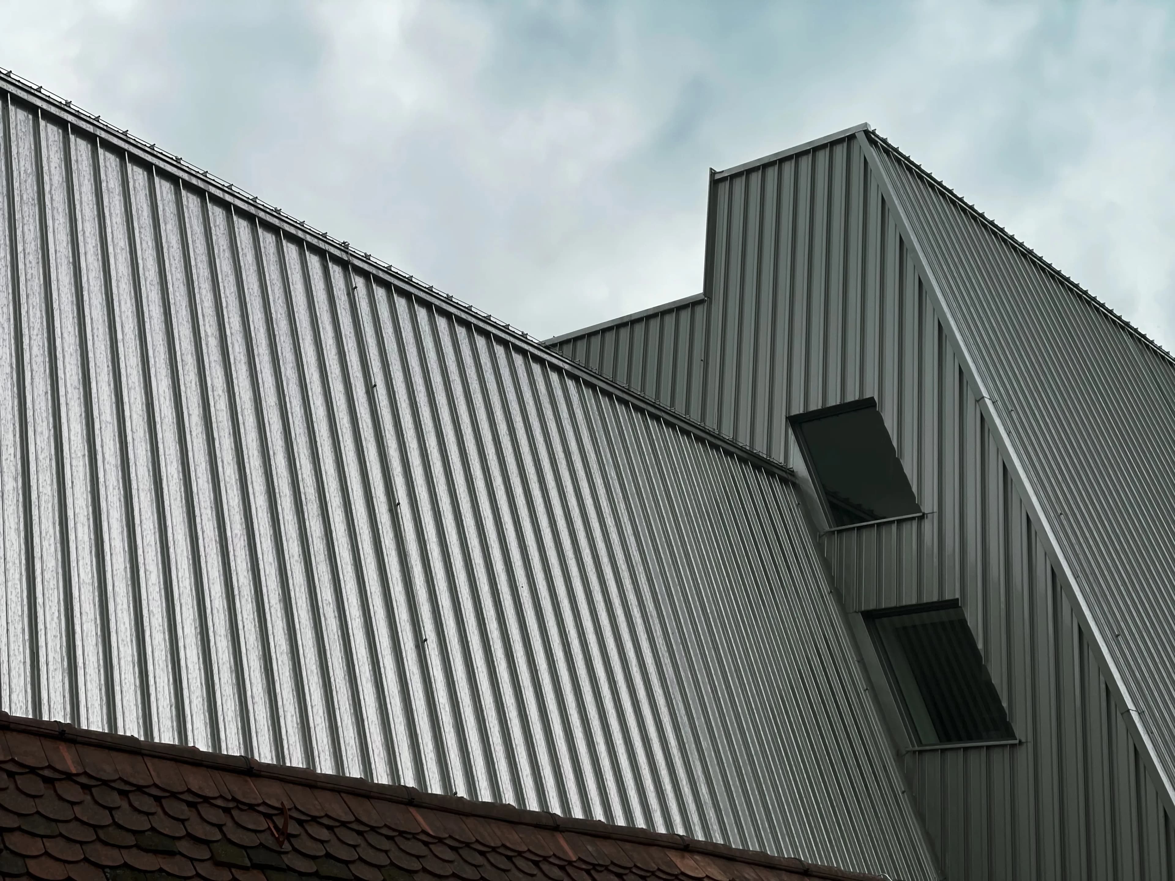 Angular corrugated-metal building facade beneath a cloudy sky