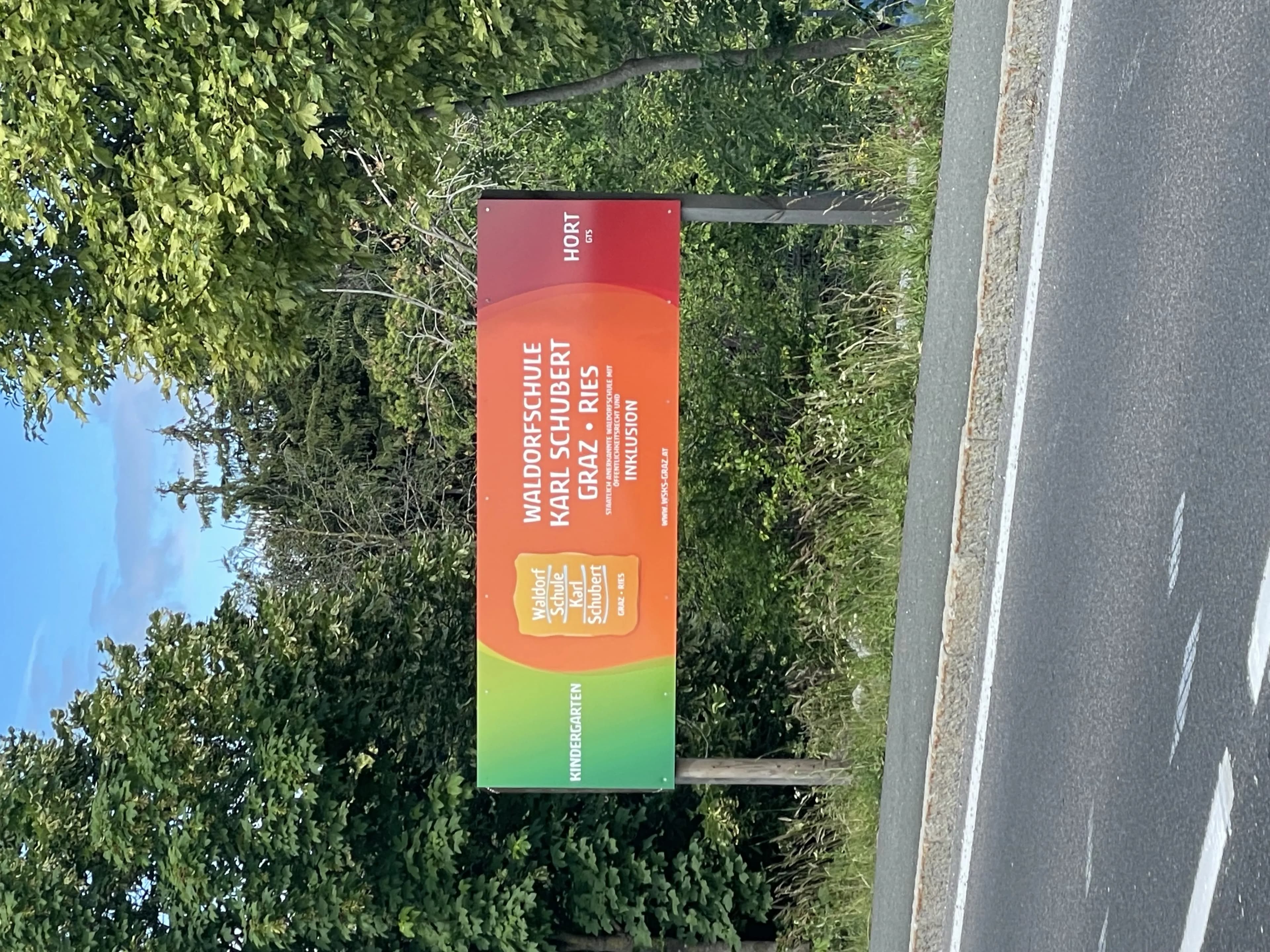 Sideways view of a colourful roadside billboard framed by green trees