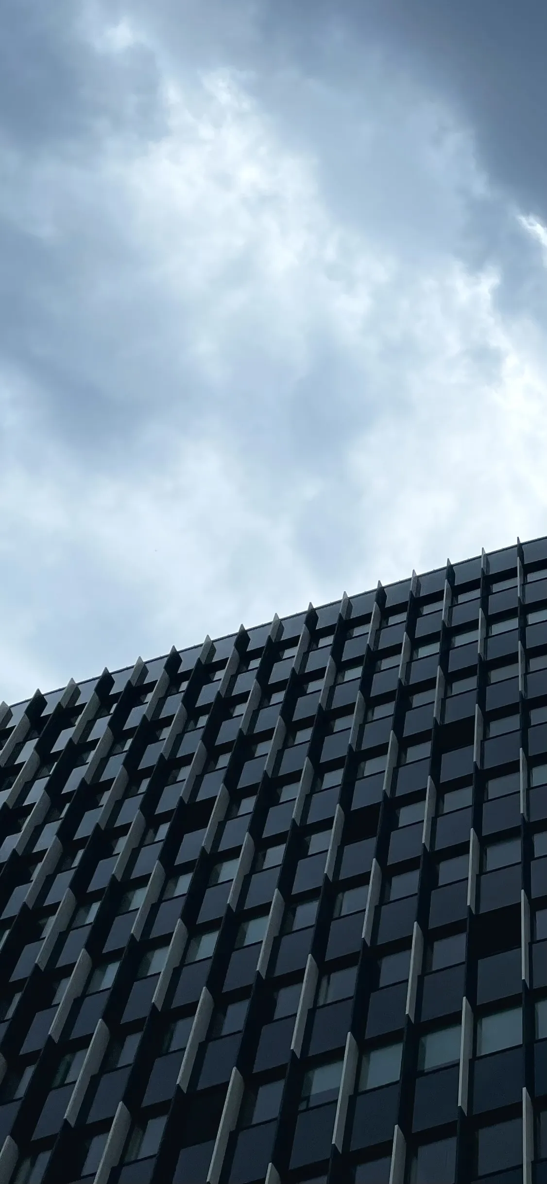 Bright clouds above the edge of a curved glass building